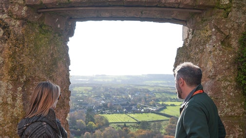 Visitors looking out of the thick stone window at the top of Corfe Castle